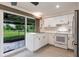 Charming kitchen featuring white cabinets, stainless steel refrigerator, and backyard access at 3497 Cohoes St, Port Charlotte, FL 33952