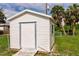 White storage shed with a door and small window in the backyard at 3497 Cohoes St, Port Charlotte, FL 33952