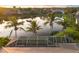 Tranquil backyard view featuring a screened enclosure, palm trees, and a serene lake backdrop at 4334 Corso Venetia Blvd, Venice, FL 34293