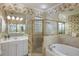 Well-lit bathroom features floral wallpaper, glass shower, and separate soaking tub at 4334 Corso Venetia Blvd, Venice, FL 34293