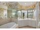 Bathroom with large mirrors reflecting custom cabinetry and soaking tub at 4334 Corso Venetia Blvd, Venice, FL 34293