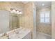 Bathroom with vanity, mirror, and shower with gold trim, and neutral floral wallpaper at 4334 Corso Venetia Blvd, Venice, FL 34293