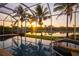 Inviting screened-in pool offers stunning sunset views over the peaceful lake and palm trees at 4334 Corso Venetia Blvd, Venice, FL 34293