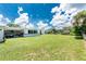 Large backyard with mature trees, lush green grass, fencing, and a covered patio perfect for outdoor entertaining at 720 Dalton Blvd, Port Charlotte, FL 33952