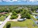 Aerial view featuring RVs parked on a lot adjacent to residential homes, surrounded by lush trees and a clear sky at 976 Great Falls Nw Ter, Port Charlotte, FL 33948