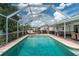 View of the screened in pool deck, outdoor kitchen, and inground pool with lounge chairs at 976 Great Falls Nw Ter, Port Charlotte, FL 33948