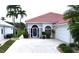 Inviting home front featuring a white tile roof, double-door entry, manicured hedges and palm trees at 10214 Arrowhead Dr, Punta Gorda, FL 33955
