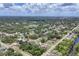 Expansive aerial view of a neighborhood with lush trees, homes, streets, and a glimpse of a waterway at 1053 Yarmouth St, Port Charlotte, FL 33952