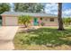 Charming home with a well-manicured lawn, complemented by tropical landscaping and a light blue front door at 1053 Yarmouth St, Port Charlotte, FL 33952