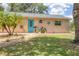 Front exterior with well-kept lawn, rock landscaping, palm trees, blue front door, and mailbox at 1053 Yarmouth St, Port Charlotte, FL 33952