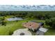 Aerial view of an estate with a circular driveway, expansive lawn, screened lanai, and picturesque lake at 10810 Wheeler Pl, Punta Gorda, FL 33950