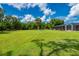 Expansive backyard with lush lawn, mature trees, and screened-in pool area providing ample space and privacy at 10810 Wheeler Pl, Punta Gorda, FL 33950