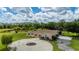 Expansive home featuring a circular driveway, screened in lanai, and tranquil lake views amidst lush landscaping at 10810 Wheeler Pl, Punta Gorda, FL 33950