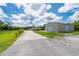 Exterior showcasing a long driveway leading to the home and a large metal building surrounded by green lawns at 10810 Wheeler Pl, Punta Gorda, FL 33950