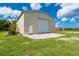 Exterior photo of the metal building featuring a roll-up door, side door, and a partial view of the home at 10810 Wheeler Pl, Punta Gorda, FL 33950