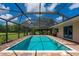 Inviting in-ground pool with screened enclosure, paver deck, and lush surroundings at 10810 Wheeler Pl, Punta Gorda, FL 33950