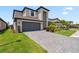Beautiful two-story home showcasing lush landscaping, a gray brick driveway, and a large two-car garage at 11105 Balfour E St, Venice, FL 34293