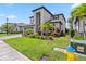 Landscaped front yard of a modern two-story home featuring palm trees, shrubs, and a lush green lawn on a sunny day at 11105 Balfour E St, Venice, FL 34293
