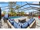 A screened pool area with a large pool, spa, seating, an outdoor game table and an outdoor kitchen setup at 11105 Balfour E St, Venice, FL 34293