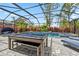 The screened pool area features a pool table, seating, and lush landscaping at 11105 Balfour E St, Venice, FL 34293