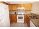 Galley kitchen features granite countertops, tile backsplash, white appliances, and ample wood cabinetry at 1128 Rum Cay Ct, Punta Gorda, FL 33950