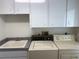 A laundry room with a washer, dryer, sink, countertop, and overhead cabinets at 1128 Rum Cay Ct, Punta Gorda, FL 33950