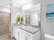 Bathroom featuring granite countertops, white cabinets, a large mirror, and glass enclosed shower at 14081 Heritage Landing Blvd # 214, Punta Gorda, FL 33955