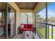 Comfortable balcony with red sofa, table, and views of lush landscaping and parking area at 19505 Quesada Ave # Vv201, Port Charlotte, FL 33948