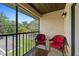 Inviting balcony featuring red wicker chairs, a table, and scenic views of trees and blue sky at 19505 Quesada Ave # Vv201, Port Charlotte, FL 33948