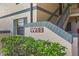 Close-up of building entrance with stairs, showing apartment numbers, textured walls, and manicured green shrubs at 19505 Quesada Ave # Vv201, Port Charlotte, FL 33948