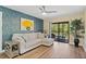 Comfortable living area with a modern sofa, decorative blue wall, and sliding glass doors to a private balcony at 19505 Quesada Ave # Vv201, Port Charlotte, FL 33948