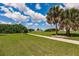 Lush green backyard with sidewalk and mature palm trees creating a serene outdoor space at 2105 Deborah Dr, Punta Gorda, FL 33950