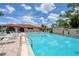 Community pool with plenty of chairs and a clubhouse with lush green landscaping at 23465 Harborview Rd # 214, Punta Gorda, FL 33980