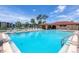 Large community pool with plenty of lounge chairs and a clubhouse under the sunny skies at 23465 Harborview Rd # 214, Punta Gorda, FL 33980