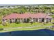 A view of the condos featuring lush landscaping, palm trees, and a serene lake view in the community at 23465 Harborview Rd # 214, Punta Gorda, FL 33980