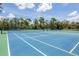 Outdoor tennis courts with well-maintained blue surface ready for a match on a sunny day with some trees in the background at 23465 Harborview Rd # 214, Punta Gorda, FL 33980