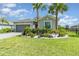 Charming single-story home with lush landscaping, vibrant flowers, and two mature palm trees at 24348 Nicobar Ln, Punta Gorda, FL 33955