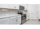 Well-lit kitchen featuring white cabinets, stainless steel appliances, and a stylish backsplash design at 24348 Nicobar Ln, Punta Gorda, FL 33955