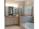 Bright bathroom featuring a dual sink vanity, glass enclosed shower, and soaking tub with tile surround at 25224 Lahore Ln, Punta Gorda, FL 33983