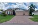 Charming single-story home with a stone facade and a three-car garage and a beautifully paved brick driveway at 25224 Lahore Ln, Punta Gorda, FL 33983