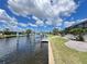 Backyard view showing lawn, foliage, screened lanai, and dock on a waterfront property at 2526 Brazilia Ct, Punta Gorda, FL 33950