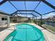 A screened-in pool features clear turquoise water and overlooks a canal with tropical landscaping at 2526 Brazilia Ct, Punta Gorda, FL 33950