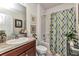 Bright bathroom featuring a stylish vanity, decorative mirrors, and a shower-tub combination with a patterned curtain at 25272 E Lenox Cir, Punta Gorda, FL 33950