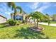 Landscaped front yard featuring beautiful green grass and mature landscaping, enhancing curb appeal at 25272 E Lenox Cir, Punta Gorda, FL 33950