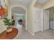 Bright hallway with arched entryway into the dining and living area with tile flooring and white door at 25272 E Lenox Cir, Punta Gorda, FL 33950