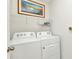 Well lit laundry room with shelving above the washer and dryer at 25272 E Lenox Cir, Punta Gorda, FL 33950