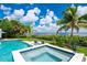 Inviting pool and spa area with a serene water view, surrounded by lush landscaping and lounge chairs at 25462 Shore Dr, Punta Gorda, FL 33950