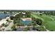 Community aerial view showcasing tennis courts, pool, lake, and green golf course amid lush landscaping and parking at 26254 Stillwater Cir, Punta Gorda, FL 33955