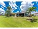 Beautifully landscaped backyard with a spacious lawn, tropical palm trees, and a screened lanai, offering a serene outdoor retreat at 26254 Stillwater Cir, Punta Gorda, FL 33955