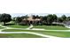 An exterior view of a building shows a beautifully landscaped setting with a walking path and lush green grass at 26254 Stillwater Cir, Punta Gorda, FL 33955